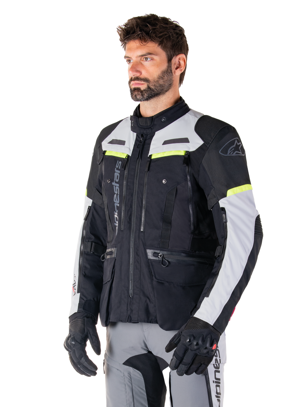 Alpinestars Bogotá Pro Drystar® Jacket, adventure touring motorcycle jacket, Black Ice Gray and Yellow Fluo, worn by a man with matching gray pants and black gloves, featuring technical ventilation panels and multi-pocket design.