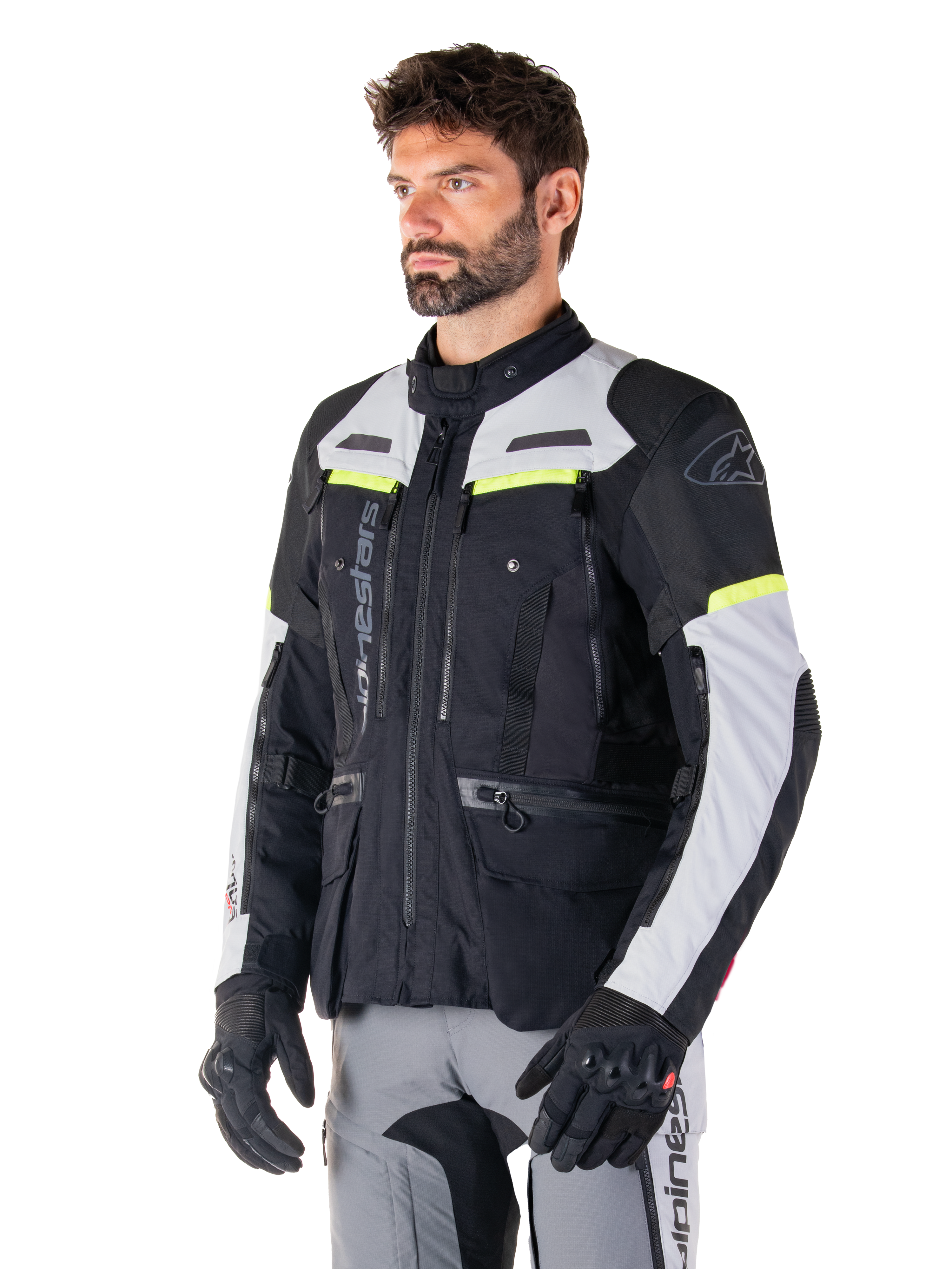 Alpinestars Bogotá Pro Drystar® Jacket, adventure touring motorcycle jacket, Black Ice Gray and Yellow Fluo, worn by a man with matching gray pants and black gloves, featuring technical ventilation panels and multi-pocket design.