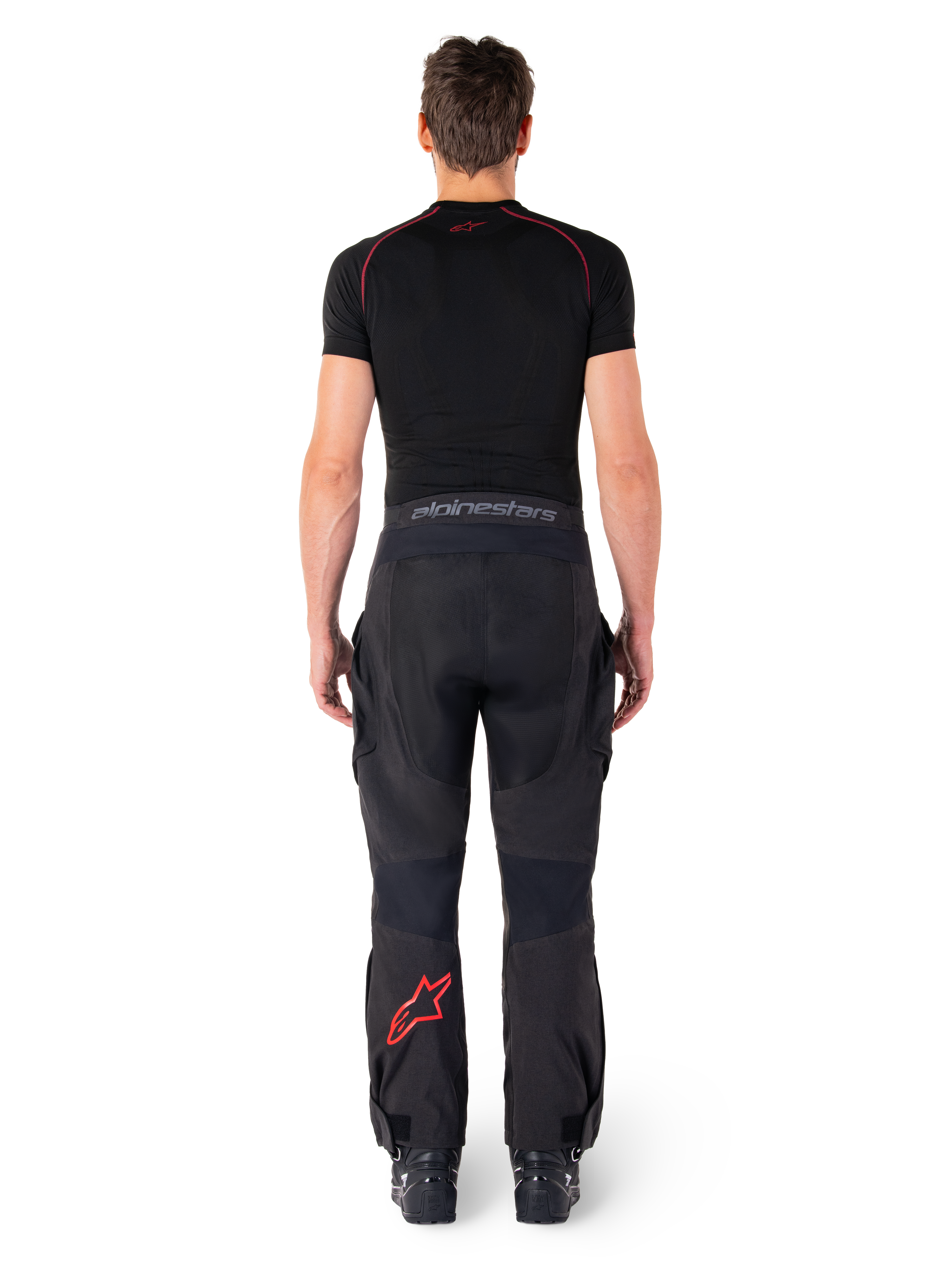 Alpinestars Hyde Xt Drystar® Pants, Adventure Touring Motorcycle Pants, Black and Bright Red, rear view of a rider wearing the pants and a black base layer, featuring a red star logo on the left leg and grey branding on the waistband.