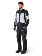 Alpinestars ST-1 Waterproof Pants, Black, worn by a male model with a grey and neon yellow touring jacket, black gloves and boots, featuring a textile design with the Alpinestars logo on the thigh, designed for all-weather adventure touring
