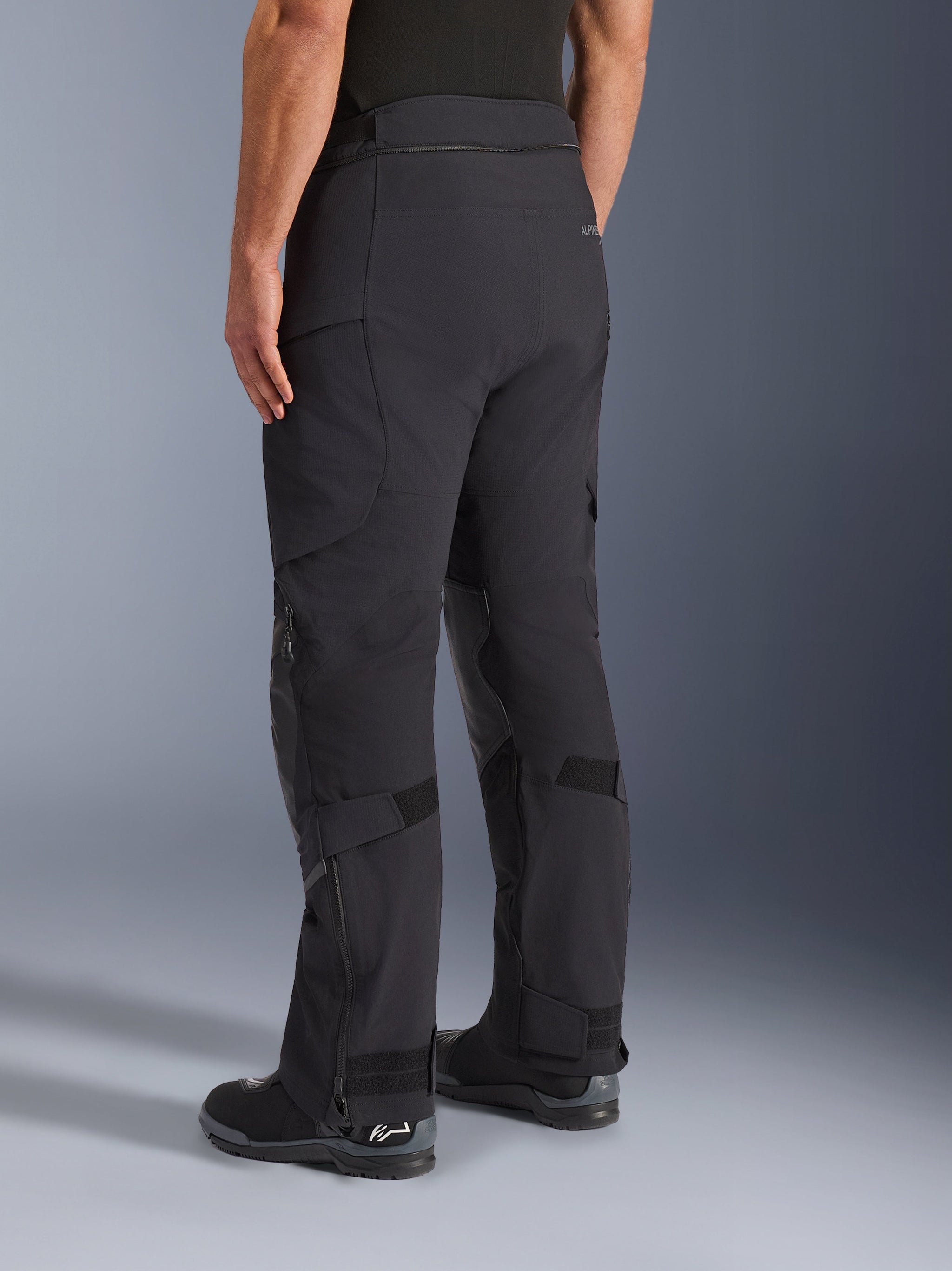 Alpinestars Andes Pro Drystar® XF Pants, Adventure Touring Pants, Black and Dark Gray, rear three-quarter view showing textile construction, zippered lower legs with adjustable calf straps, and integrated riding boots