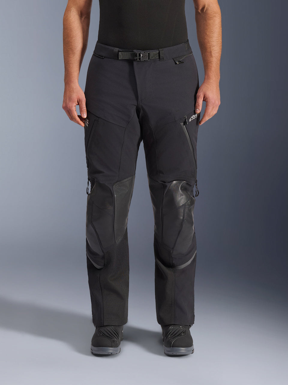 Alpinestars Andes Pro Drystar® XF Pants, Black Dark Gray adventure touring motorcycle pants, front view, featuring 3-layer laminated construction, integrated knee armor panels, waterproof zippered pockets, and magnetic waist buckle, styled with black riding boots.