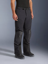 Alpinestars Andes Pro Drystar® XF Pants, Adventure Motorcycle Pants, Black and Dark Gray, worn by a model with black riding boots, featuring reinforced knee panels, adjustable waist belt with magnetic buckle, zippered pockets, and a durable laminated textile construction for all-weather riding
