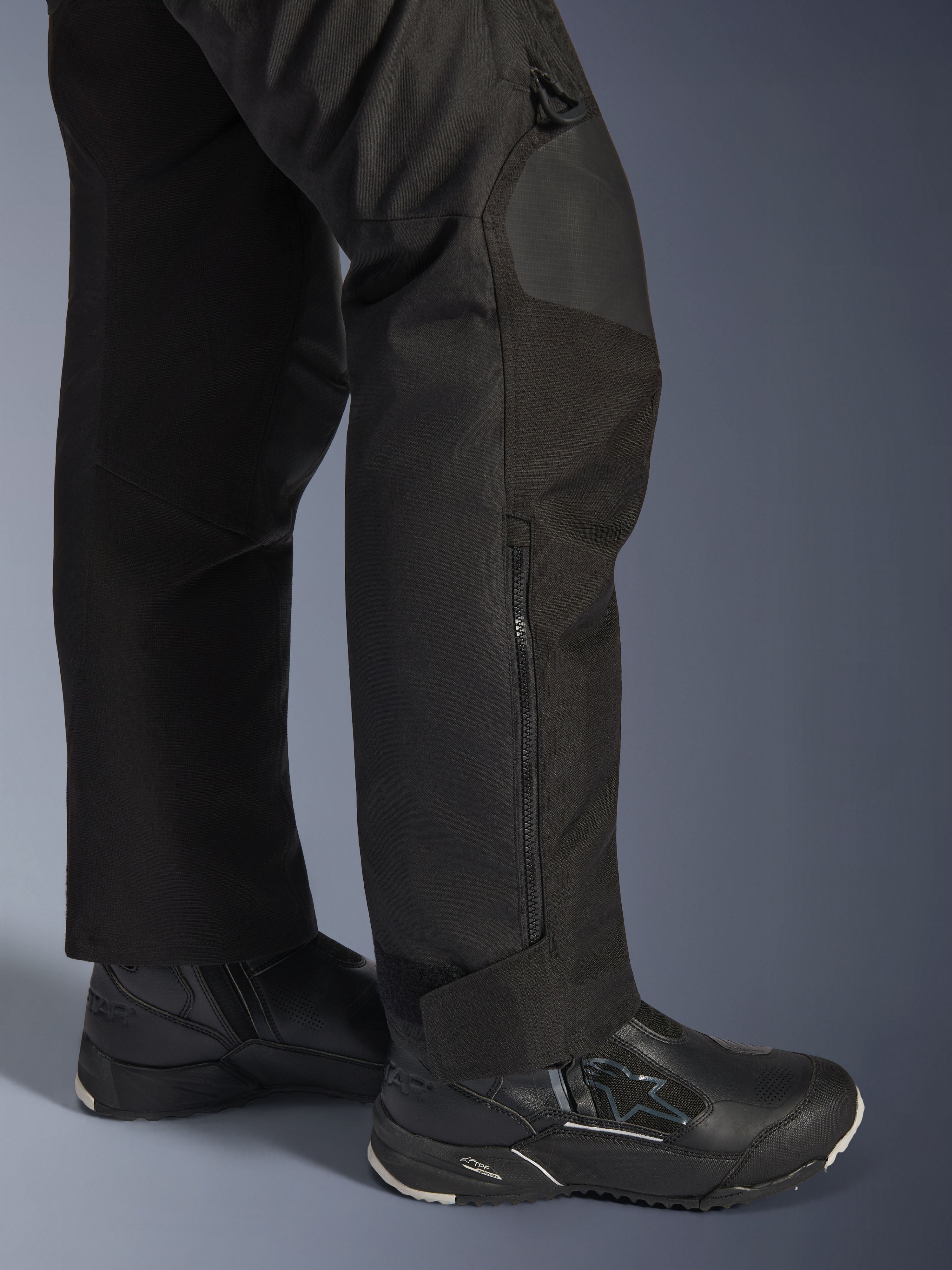 Alpinestars Stella Andes V4 Drystar® Pants, Woman's Motorcycle Pants, Black, close-up of lower leg featuring side zipper and adjustable ankle cuff, worn with black Alpinestars riding boots
