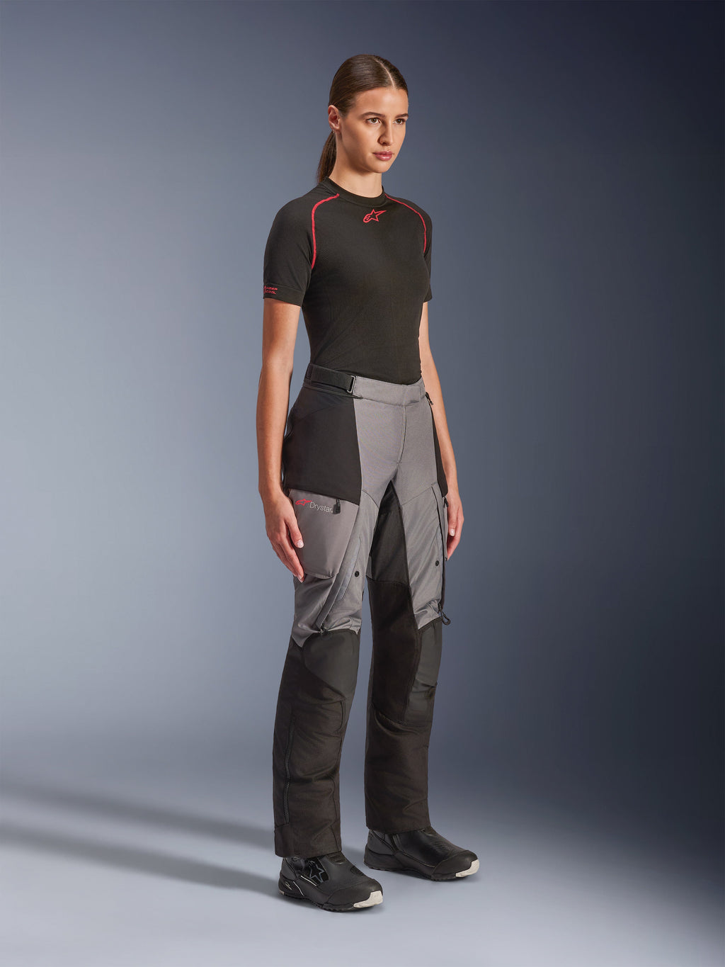 Alpinestars Stella Andes V4 Drystar® Pants, Women's Adventure Motorcycle Pants, Black and Dark Gray, worn by a model with a black Alpinestars base layer and black boots, featuring reinforced panels, red Drystar logo, and cargo pockets.