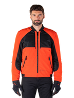 Alpinestars Mootant Waterproof Parka in Spicy Orange and Black, modular motorcycle jacket shown in a bomber-style configuration on a male model, featuring black mesh upper chest panels, bright orange torso and sleeves, front zipper, and ribbed collar, paired with black gloves and trousers