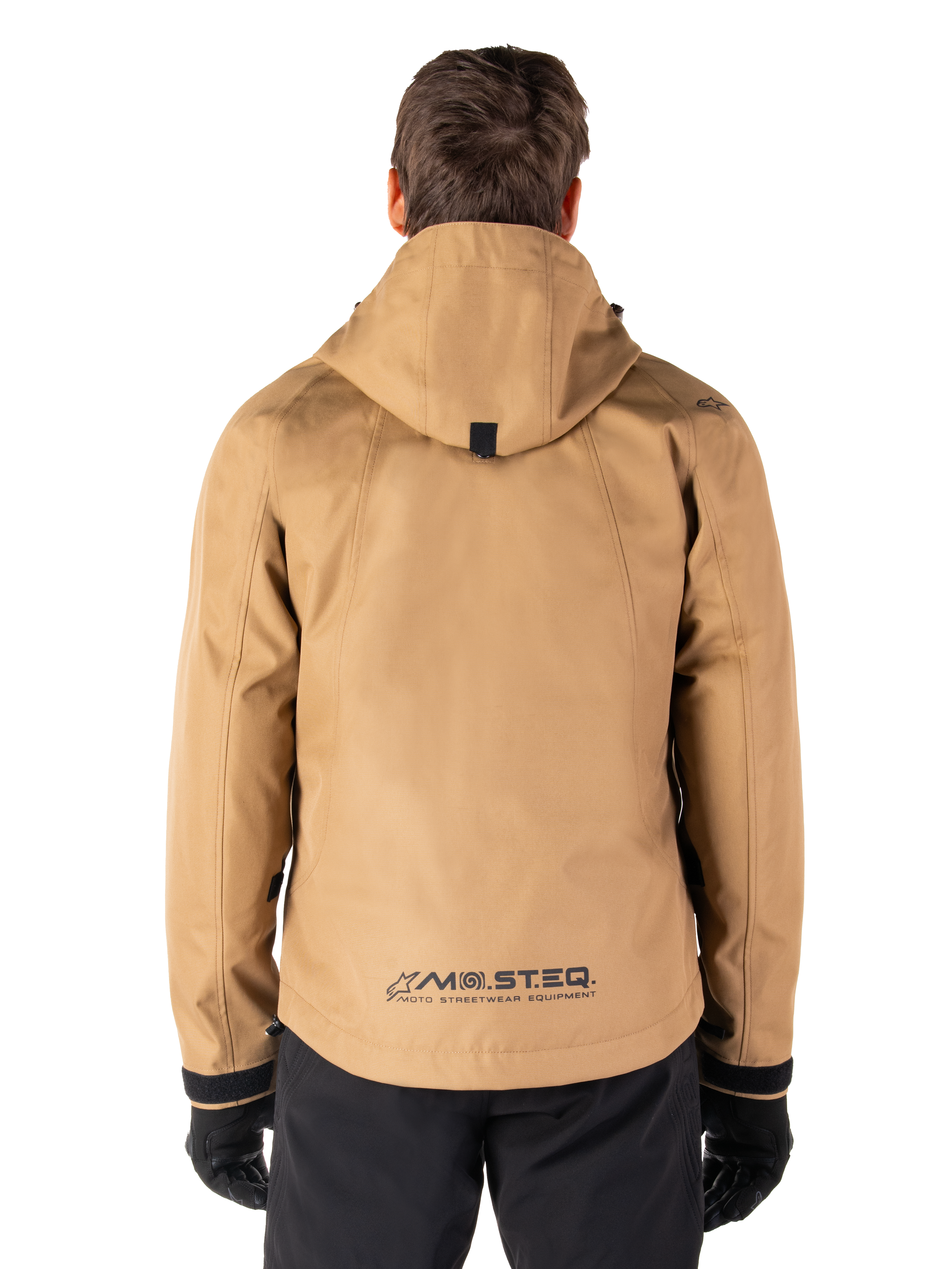 Alpinestars Morush Waterproof Parka, Utility Brown, rear view, featuring a hood and MO.ST.EQ. branding on the lower back, paired with black pants and gloves, modern streetwear-inspired motorcycle gear