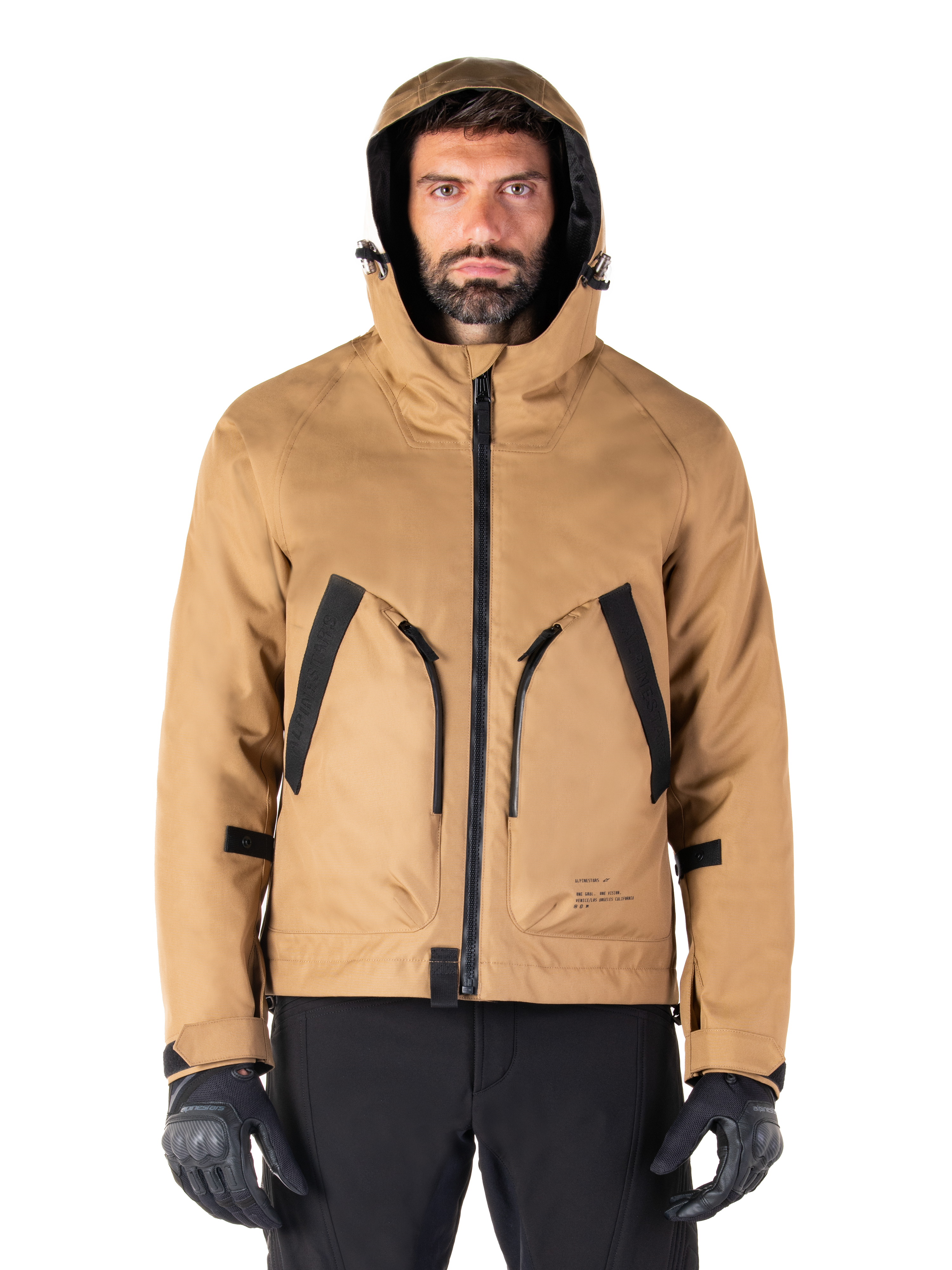 Alpinestars Morush Waterproof Parka, Motorcycle Jacket, Utility Brown, hooded streetwear-inspired design with large black-accented front pockets, worn with black riding gloves and pants, urban contemporary motorcycle gear