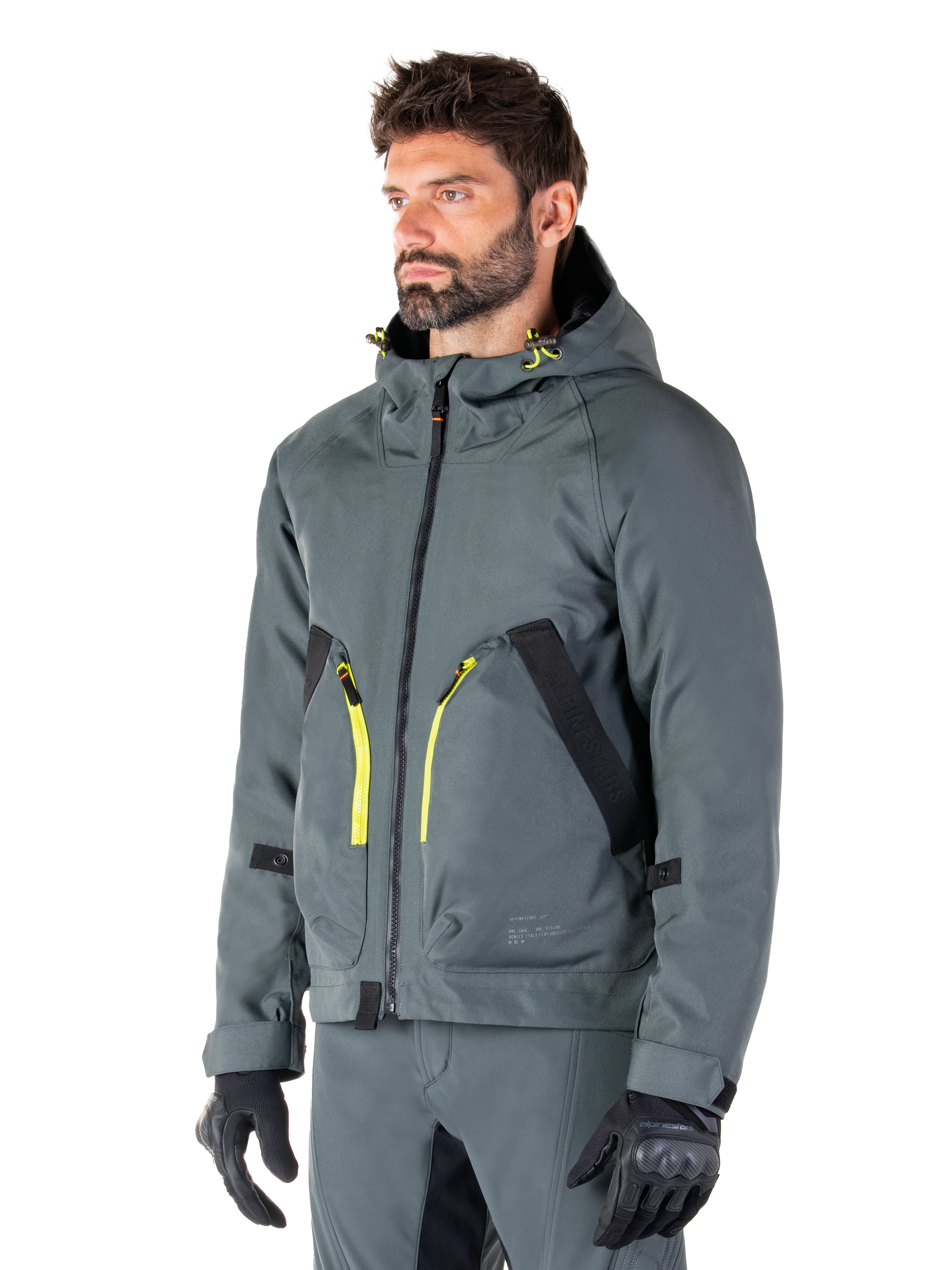 Alpinestars Morush Waterproof Parka, Urban Gray motorcycle jacket, hooded design with bright yellow zipper accents, black pocket detailing, worn with matching gray riding pants and black gloves, contemporary streetwear-inspired motorcycle apparel.