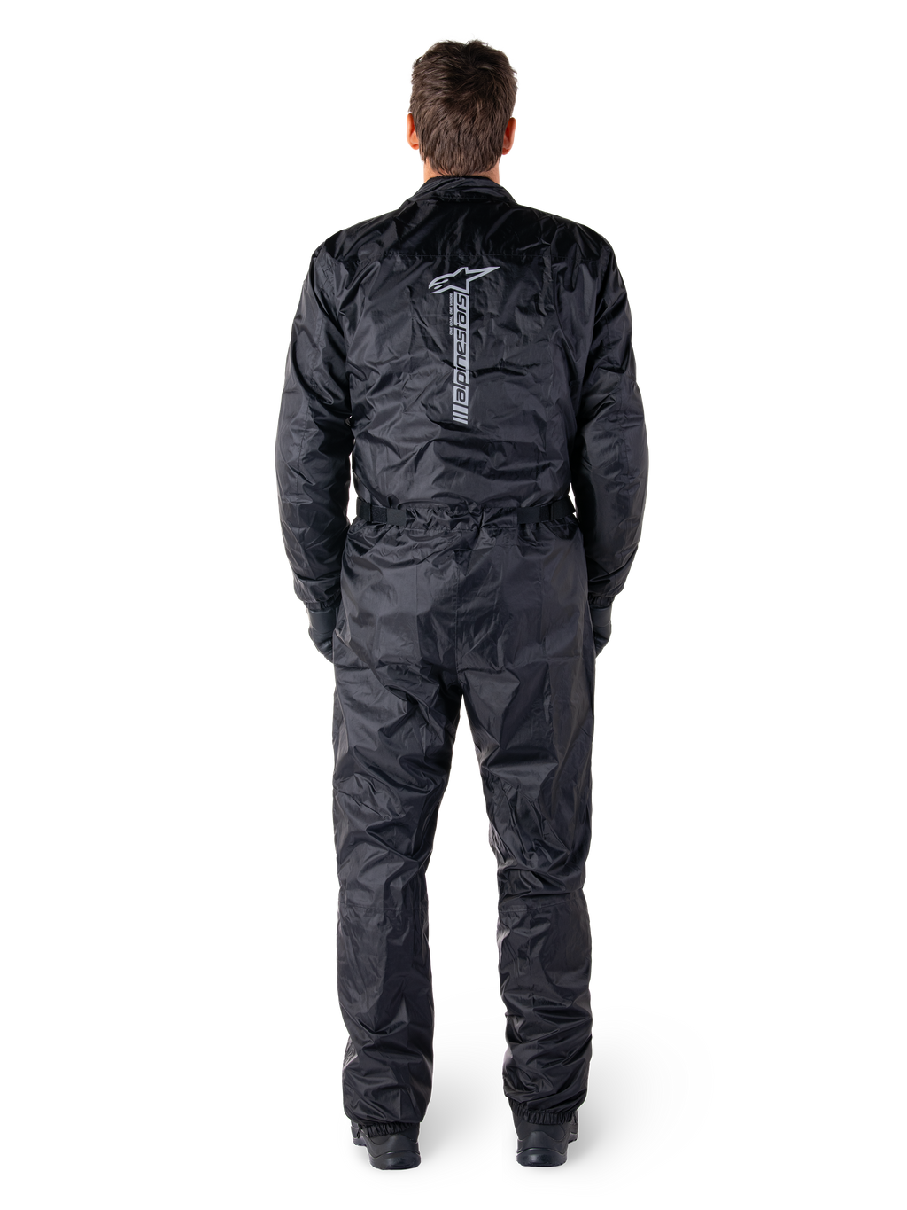 Alpinestars Hurricane Rain V2 Suit, Black One-Piece Waterproof Motorcycle Suit, back view showing large vertical Alpinestars wordmark and logo, lightweight crinkled fabric with elasticated waist and cuffs, designed for wet weather riding protection.