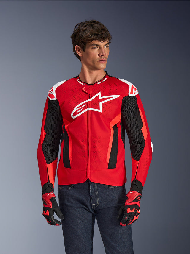 Alpinestars T-GP Air Jacket, Motorcycle Riding Jacket, Bright Red and Black with White Logo, featuring perforated mesh ventilation panels, worn with matching gloves and dark denim jeans, sporty design for warm weather riding