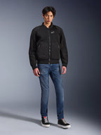 Alpinestars Flight Air Jacket, Black, urban-inspired bomber-style motorcycle jacket with 3D mesh panels and white chest logo, worn by a model with blue jeans and black sneakers, contemporary riding apparel