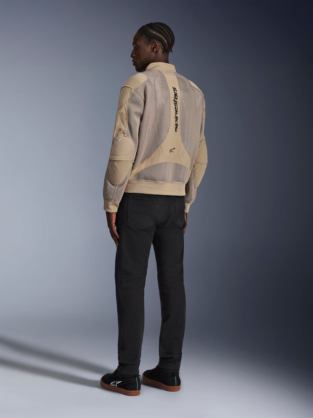 Alpinestars Flight Air Jacket, urban textile motorcycle jacket, Brown, back view showing large 3D mesh panels and vertical logo, bomber-style silhouette with ribbed collar and hem, paired with black pants and black shoes for street-inspired riding style.