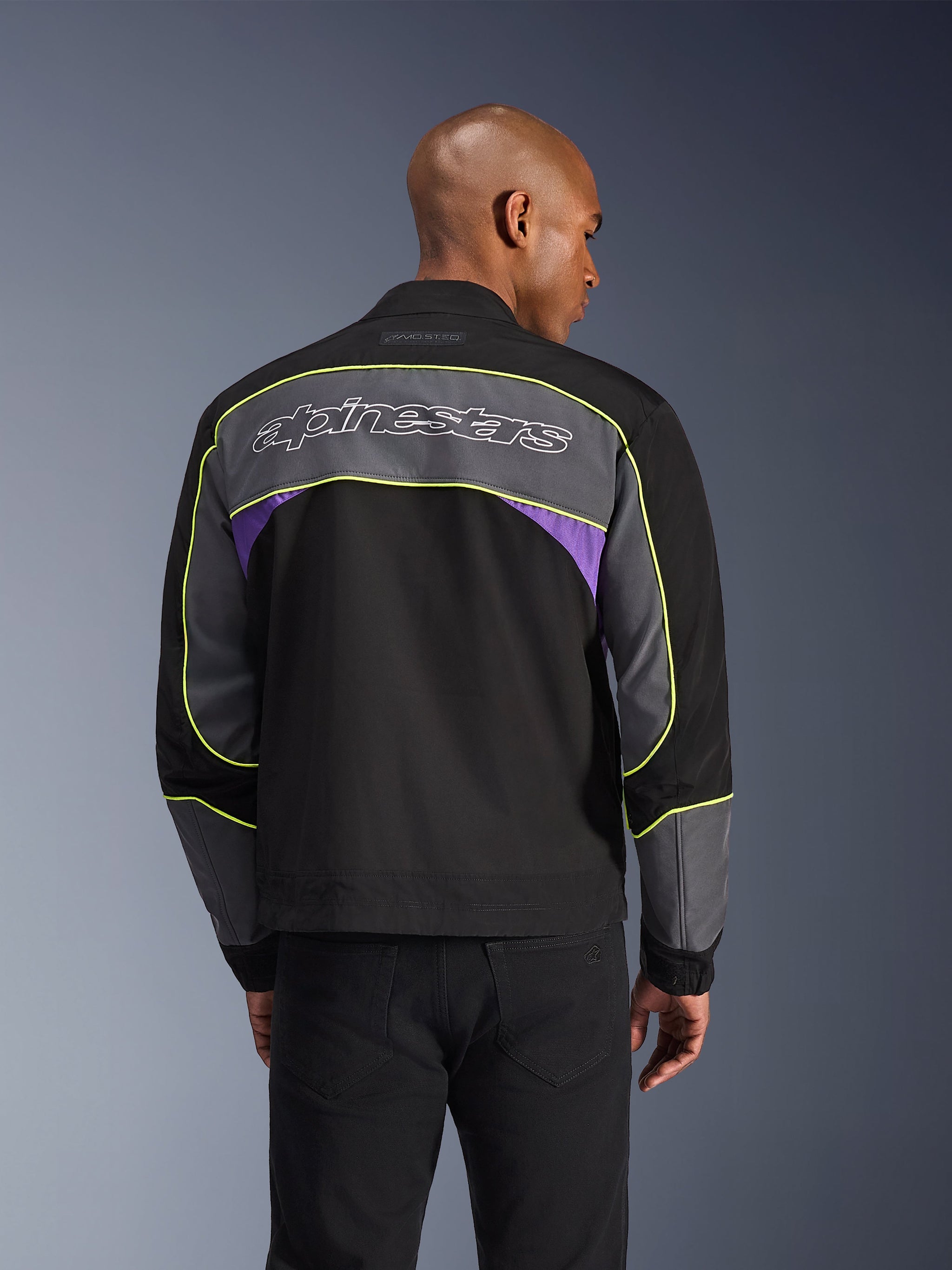 Alpinestars Unite Jacket, Urban Motorcycle Jacket, Black Asphalt Violet, back view featuring grey panels and violet accents, lime yellow piping, large Alpinestars wordmark on the upper back, minimalist streetwear design