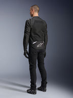 Alpinestars T-Sps Air V2 Jacket, Textile Motorcycle Jacket, Black, rear view showing large mesh ventilation panel and white Alpinestars logo on the lower back, paired with black riding pants and gloves for a sporty urban look.