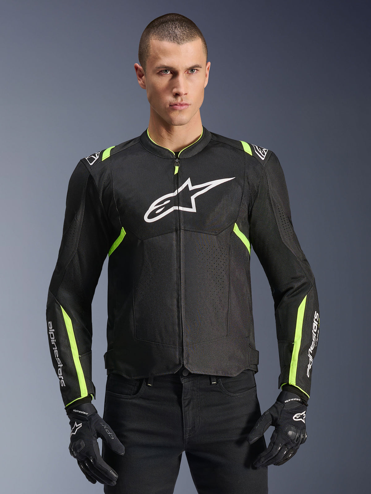 Alpinestars T-Sps Air V2 Jacket in Black Yellow Fluo, male model wearing the ventilated textile jacket with mesh panels and white chest logo, paired with black riding gloves, urban motorcycle gear