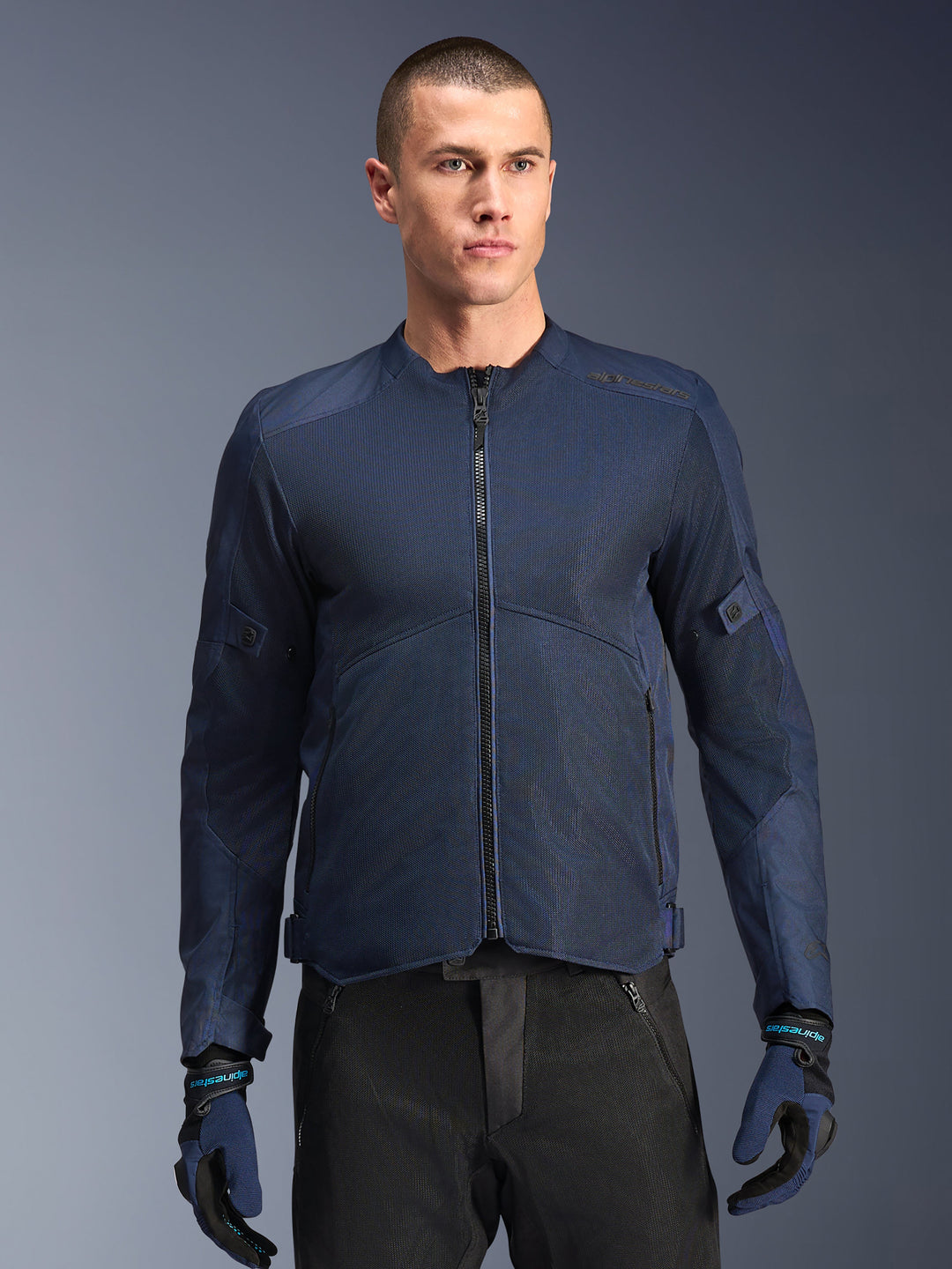 Alpinestars C-1 Air Jacket, Blue motorcycle jacket, worn by a male model with black pants and matching blue and black gloves, featuring tech mesh panels for airflow, clean urban design with front zipper and subtle branding