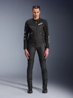 Female model wearing the Alpinestars Stella T-Dyno Air Jacket, Women's Motorcycle Jacket in Black, featuring 3D mesh panels and white Astars logos, paired with black slim-fit riding pants and black lace-up boots, urban riding gear style.