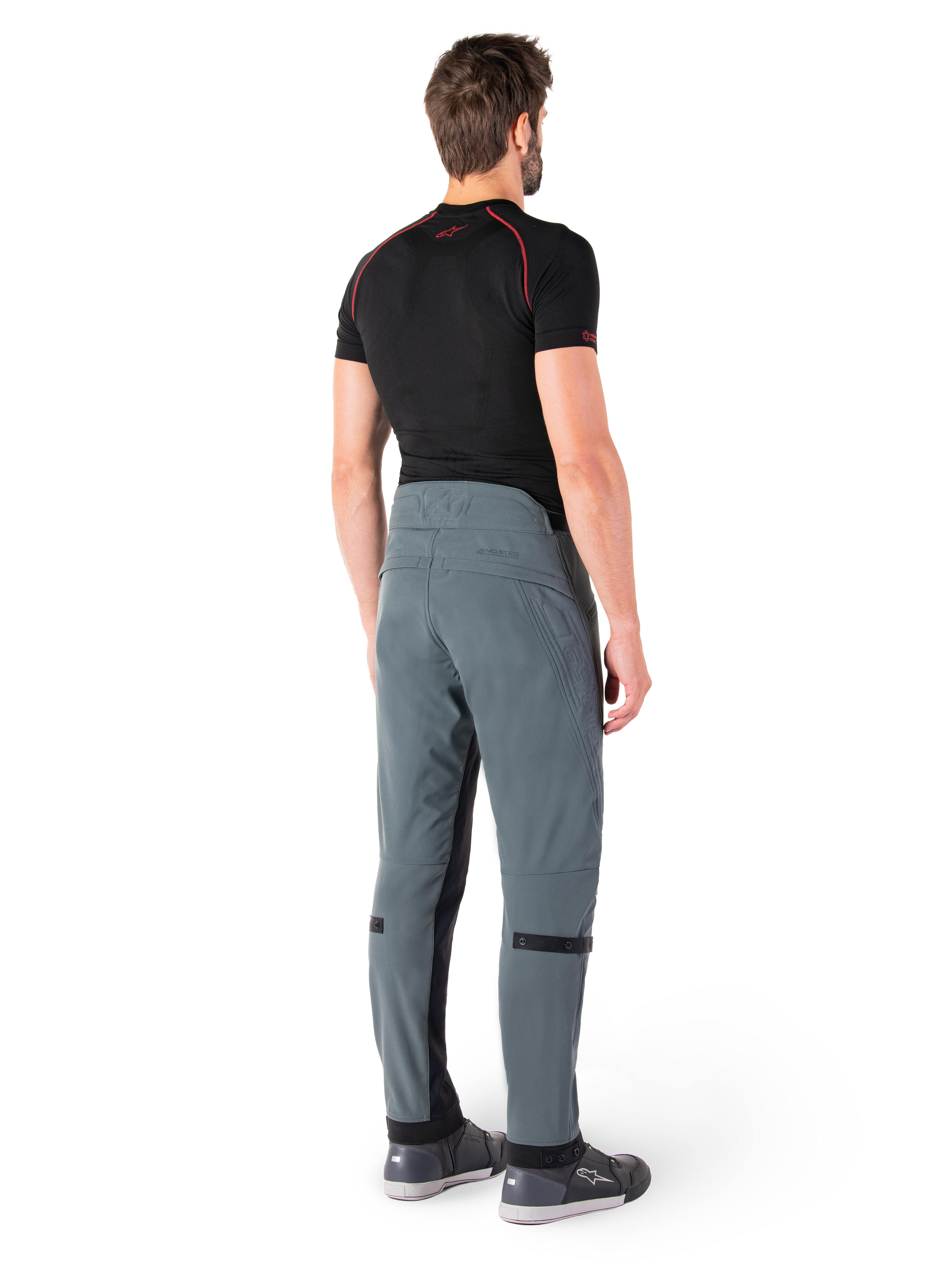 Alpinestars Alden Pants, Urban Gray, rear view, technical textile motorcycle pants with quilted detailing on the upper back waist and legs, paired with a black base layer and gray riding shoes, contemporary urban streetwear style.