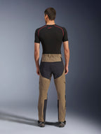 Alpinestars Flex-AST Explorer Pants, Walnut Black, rear view on model, featuring reinforced black seat and brown stretch textile, paired with black base layer and technical motorcycle boots, durable adventure riding apparel