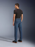 Alpinestars Flex-AST 5 Denim Pants, Indigo Washed, urban motorcycle pants with a tapered fit, shown from the rear on a model wearing a black t-shirt and sneakers, featuring a clean five-pocket design and monolayer stretch construction