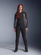 Alpinestars Stella Troop-Air Jacket and Pants, Women's Motorcycle Riding Gear, Black with Ash Gray and Pink Fluo accents, worn by a female model with red hair, featuring mesh ventilation and protective design, studio standing pose.