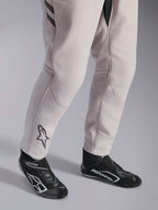 Alpinestars GP Race V3 Suit FIA, Silver Anthracite auto racing suit, detail shot of lower legs and black racing boots, featuring the black Astars logo on the calf, professional motorsport gear with ribbed cuffs