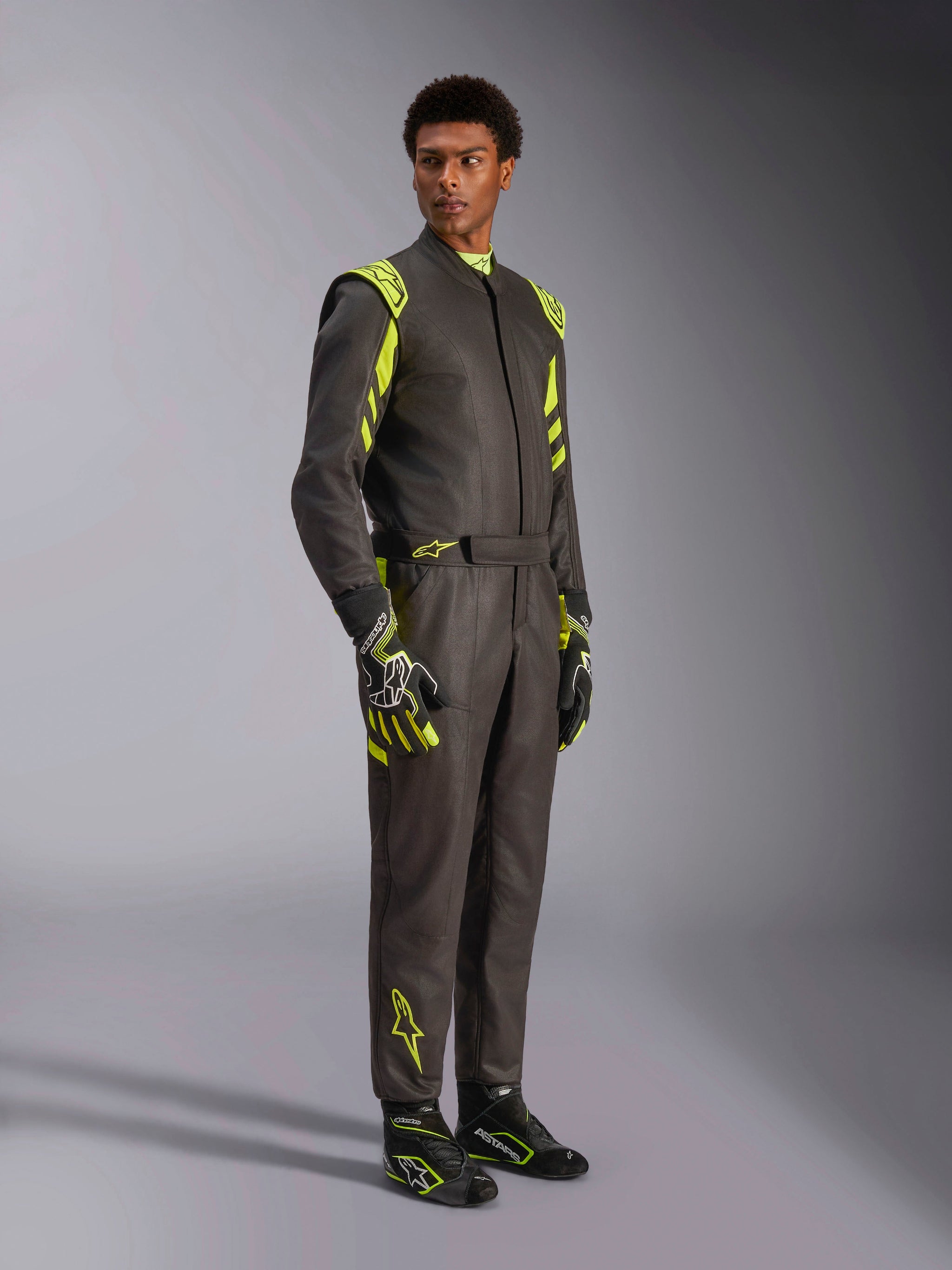 Alpinestars GP Race V3 Suit FIA, Auto Racing Suit, Black and Yellow Fluo, worn by a model with matching racing gloves and boots, featuring vibrant yellow accents on the shoulders and legs, professional motorsport gear