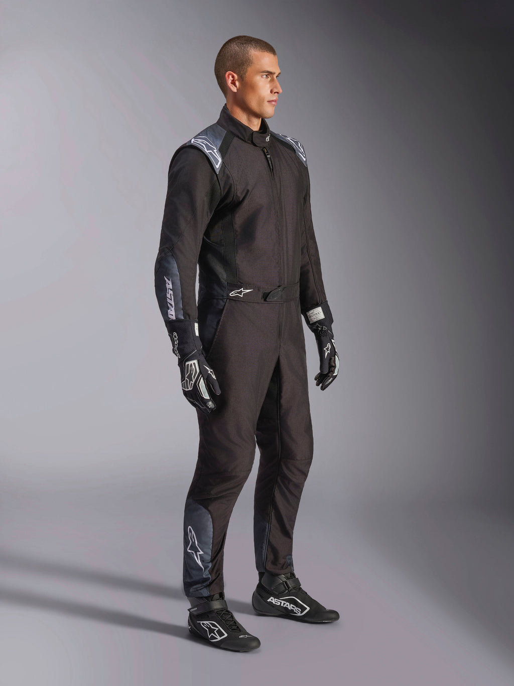 Alpinestars KMX-5 V3 Suit, Karting Suit in Black Dark Shadow, worn with matching black racing gloves and shoes, featuring laser-cut perforations and tech mesh panels, sleek dual-layer design with white branding for professional motorsport