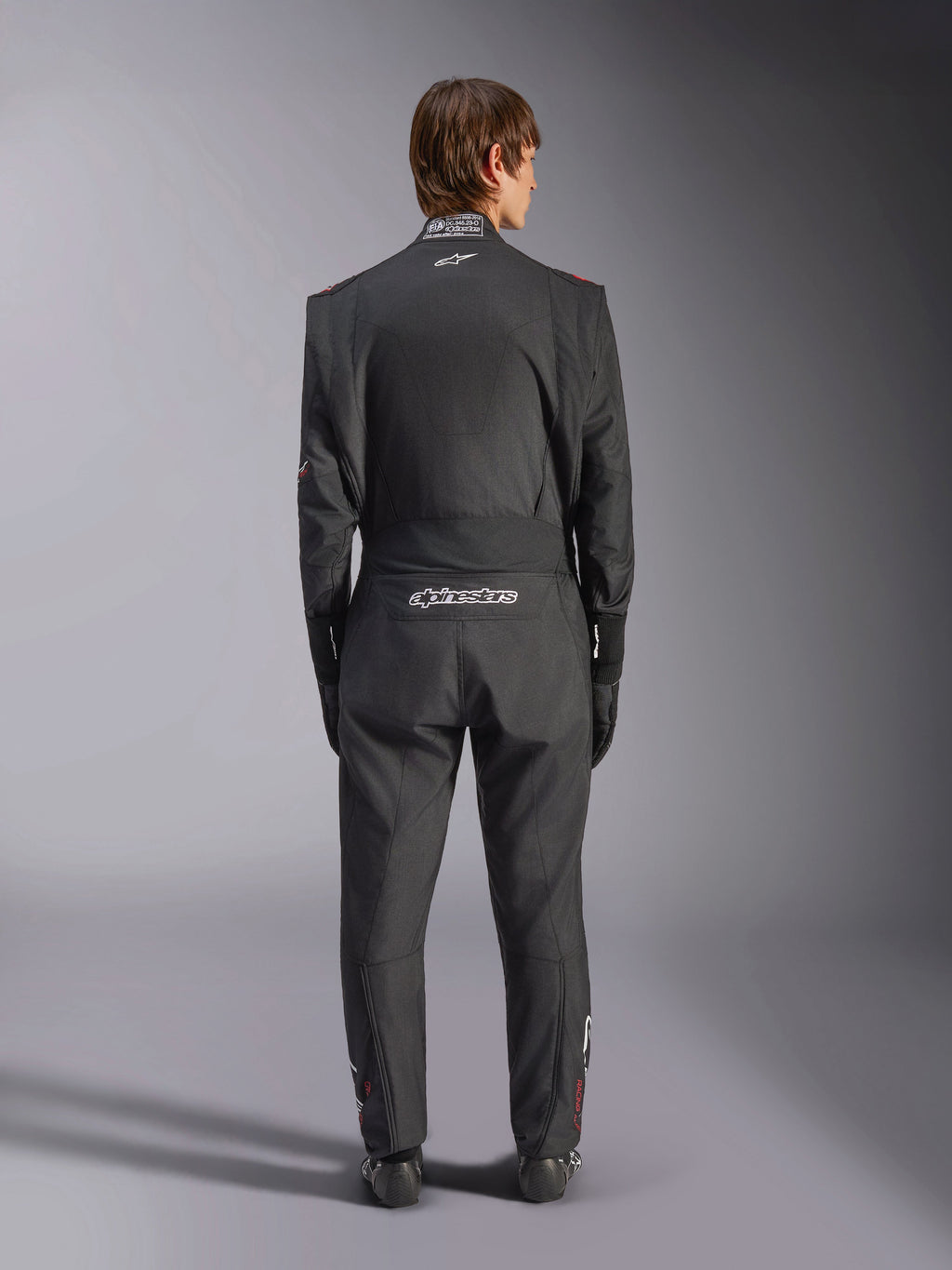 Alpinestars GP Tech V4 Suit, Auto Racing Suit, Black and White, back view featuring white Alpinestars branding and FIA certification on the collar, sleek ergonomic fit for professional driver protection