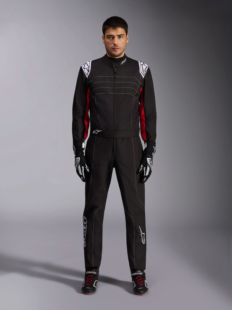 Alpinestars KMX-9 V3 Karting Suit in Black Red White, full-body front view of a model wearing the one-piece suit with coordinated racing gloves and shoes, featuring white Alpinestars logos on the shoulders and red accents.