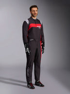 Male model wearing Alpinestars KMX-9 V3 Graphic 3 Suit, Karting Suit, Black and Red, featuring white shoulder epaulettes and red chest branding, paired with black racing gloves and shoes with red laces, professional motorsport apparel.