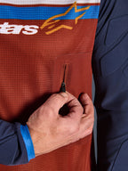 Close-up of Alpinestars Maxdura Dual Jersey, Rust Brown mesh torso with seamless zippered chest pocket, Mood Indigo sleeves with integrated padding, technical adventure motorcycle jersey detail