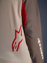 Alpinestars Maxdura Dual Jersey, Aluminum Walnut, close-up view showing the ventilated mesh torso with a red star logo and a brown abrasion-resistant sleeve with a white Alpinestars wordmark, technical adventure and dual-sport motorcycle apparel