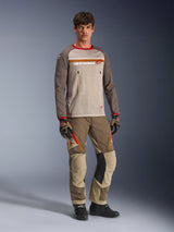 Model wearing the Alpinestars Maxdura Dual Jersey in Aluminum Walnut, featuring a grey mesh torso, brown sleeves with red cuffs, and zippered chest pockets, styled with matching off-road gear for adventure riding.