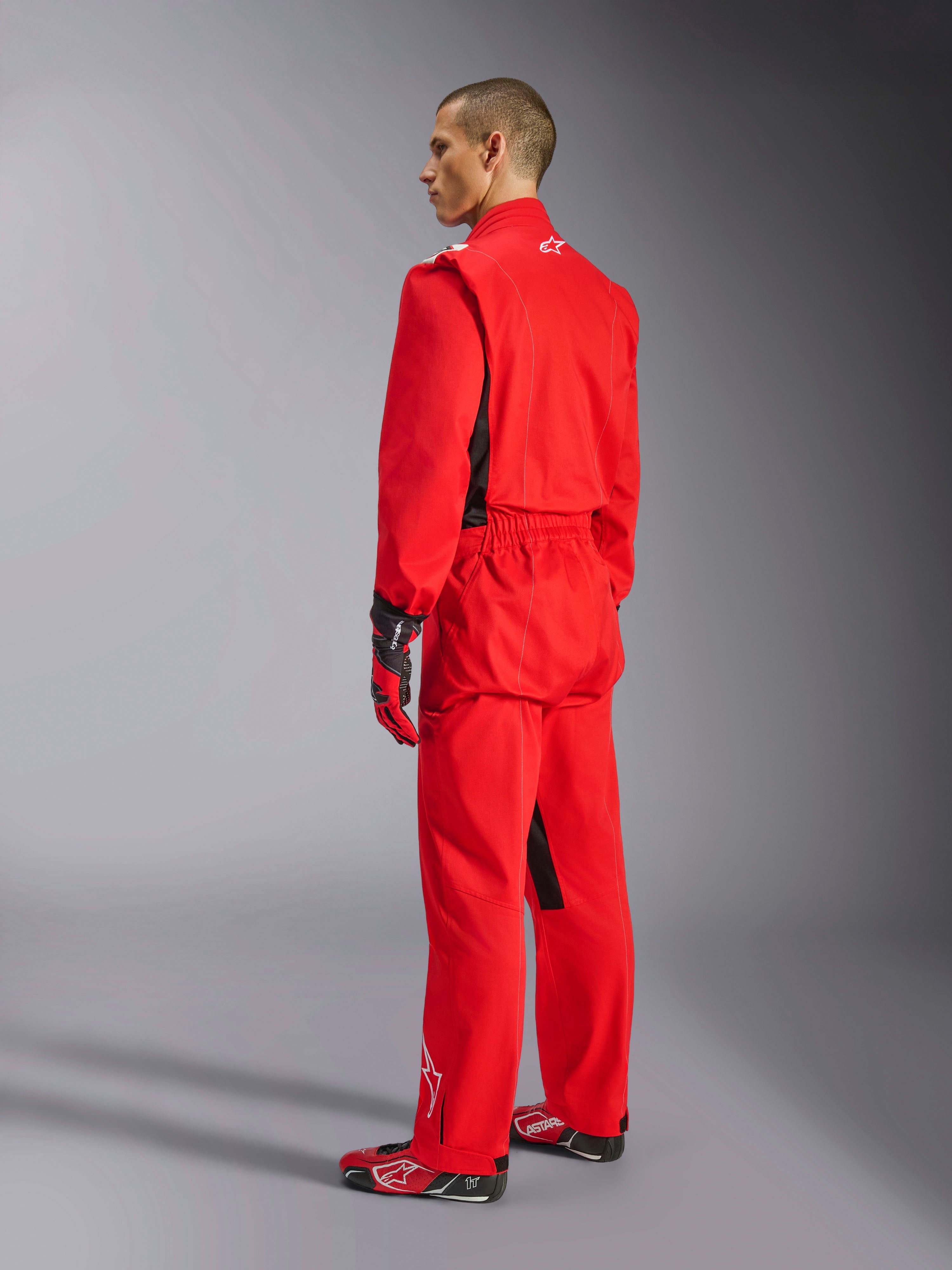Alpinestars Kart Indoor V2 Suit, Red karting suit, rear three-quarter view on a model, worn with matching red gloves and racing shoes, single-layer poly-cotton twill construction, professional motorsport gear for indoor karting.
