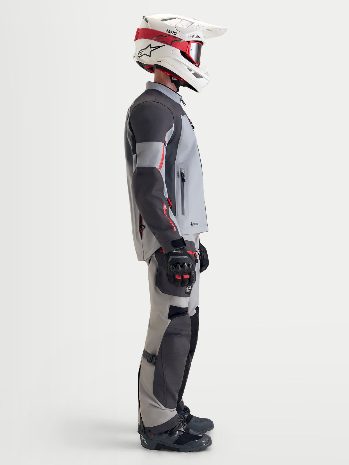 Alpinestars Arenis Gore-Tex Jacket, men's adventure touring motorcycle jacket in mid gray, deep gray, and black, side profile view of a rider wearing the waterproof textile jacket with matching gear and a white and red helmet.