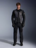 Male model wearing the Alpinestars ST-7 2L GORE-TEX Jacket in Deep Gray Black Dark Khaki, featuring 'ALPINESTARS EXPLORATION EQUIPMENT' branding on the chest, paired with matching black riding pants, gloves, and boots, studio front view.
