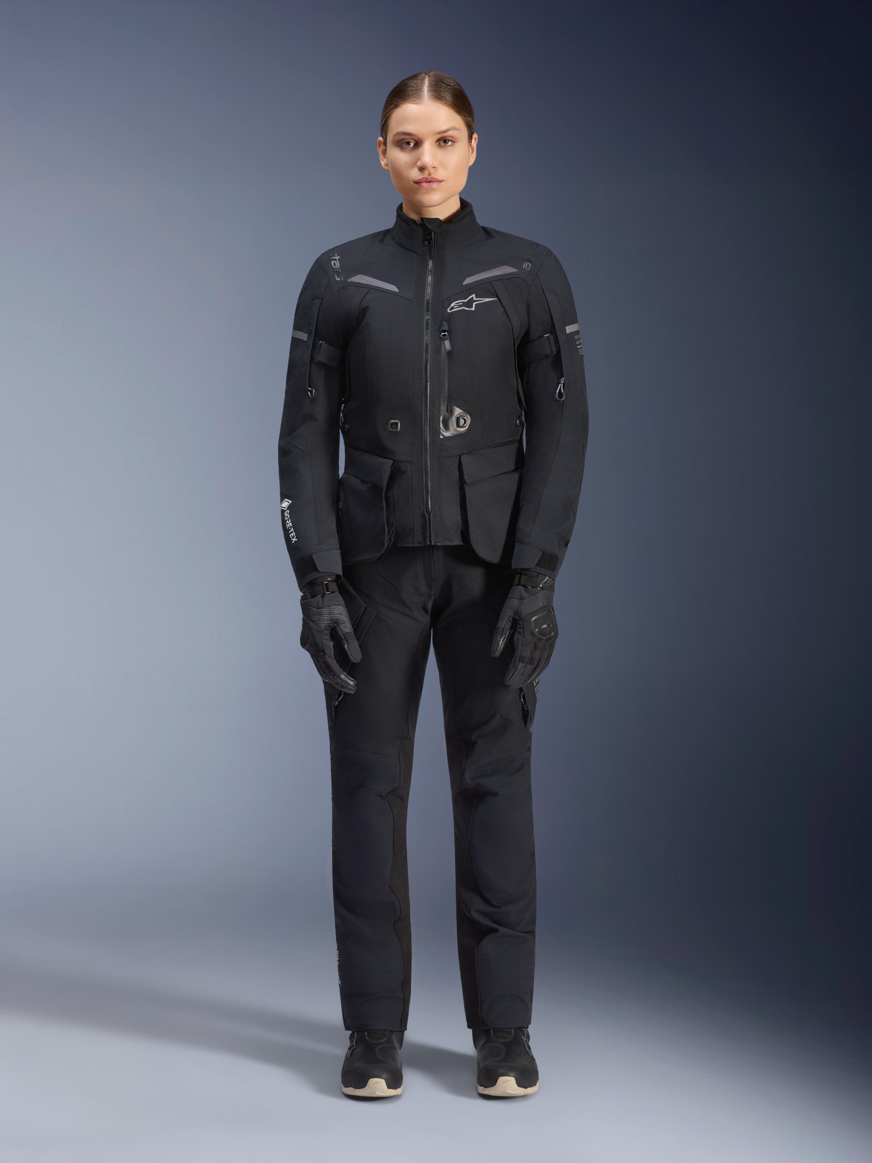 Alpinestars Stella ST-7 2L GORE-TEX Jacket, Women's Motorcycle Touring Jacket, Black and Dark Gray, worn with matching riding pants and gloves, featuring waterproof laminated shell, reflective accents, and ergonomic adventure design