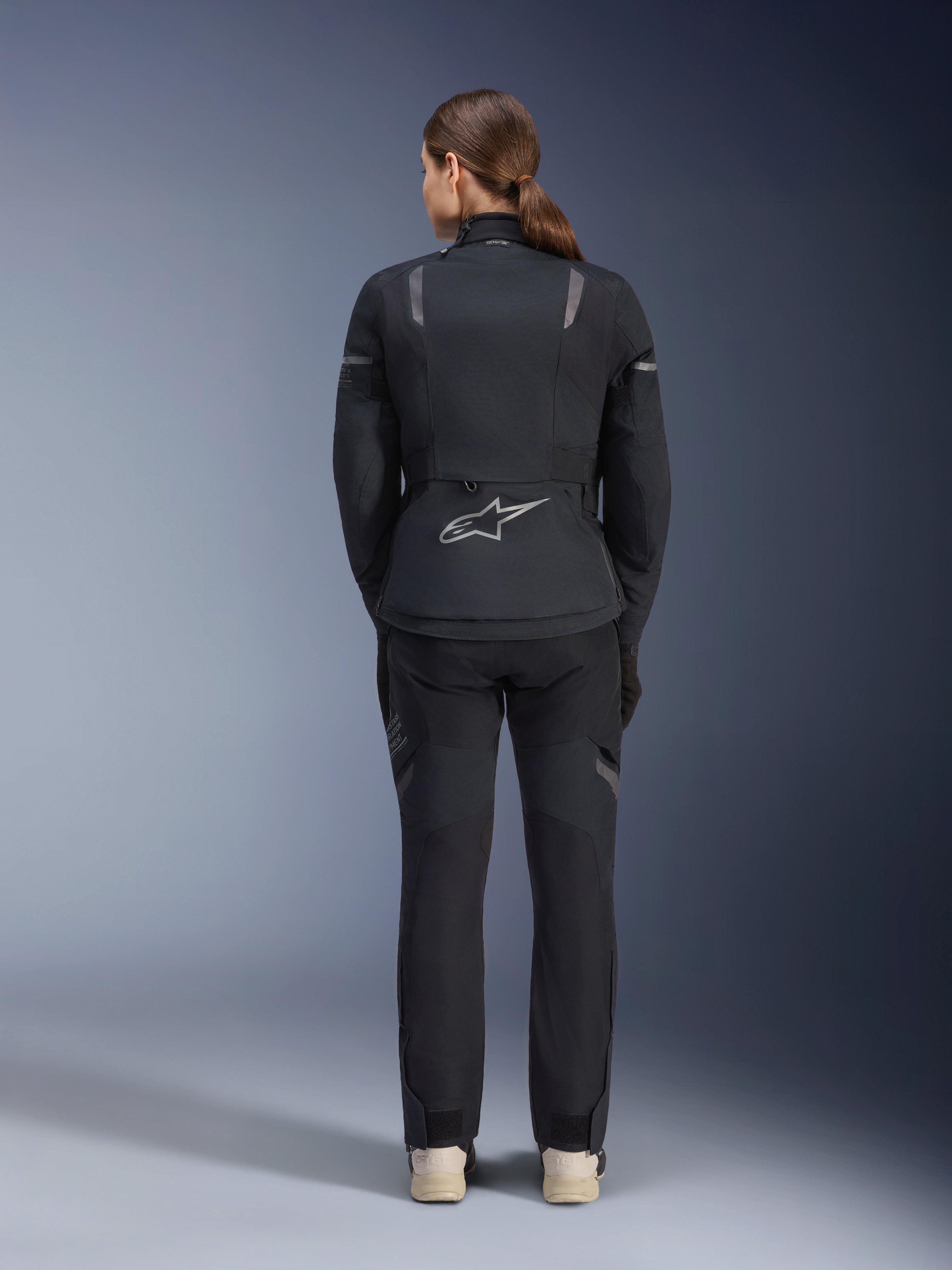 Alpinestars Women Stella ST-7 2L GORE-TEX Jacket, Black and Dark Gray, back view featuring the silver Alpinestars logo on the lower back, paired with matching black textile pants, adventure touring motorcycle gear