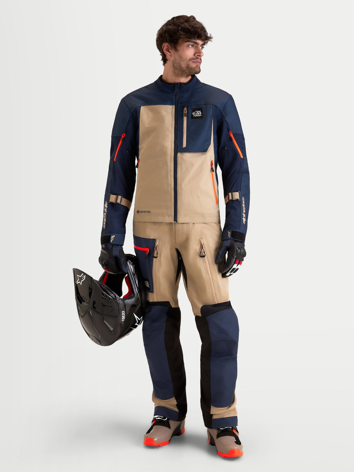 Alpinestars Arenis Gore-Tex Pants, men's adventure touring motorcycle pants in night navy and aluminum, full-length view worn by a model holding a helmet and matching adventure jacket