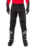 Alpinestars Pro-Dura Pants, Black and Magnet Enduro Pants, worn with a red long-sleeve jersey and black motocross boots, featuring gray Alpinestars branding and durable ripstop construction for off-road riding
