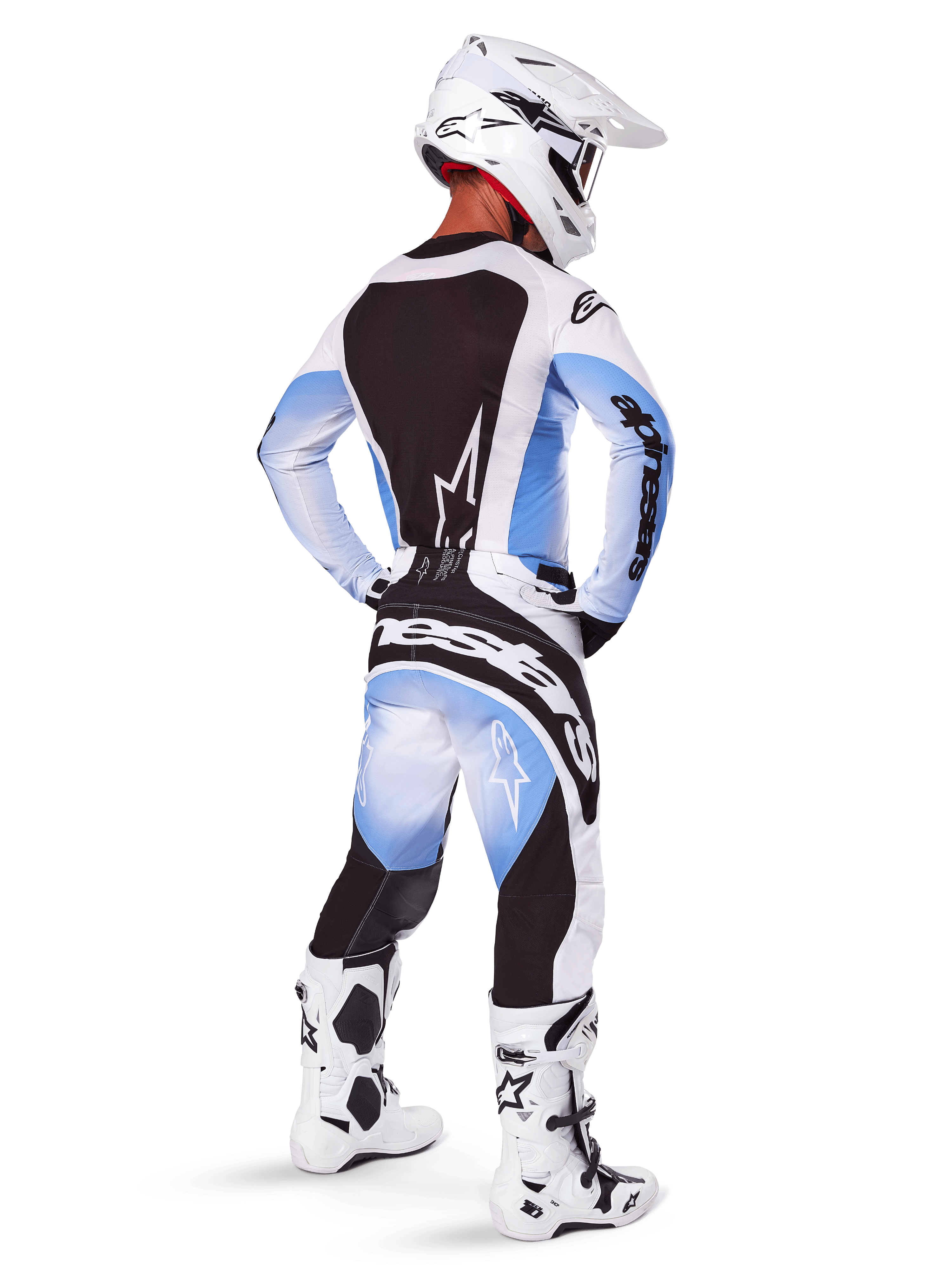 Motocross rider seen from behind wearing Alpinestars 2025 Techstar Melt Pants and jersey, Black Blue and White gradient design, white helmet, white and black boots, full off-road racing kit.
