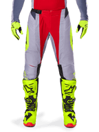 Alpinestars 2025 Techstar Melt Pants, Motocross Pants, Bright Red Gray, featuring a gray chassis with red central panels and neon yellow side accents, laser-cut perforations for ventilation, worn with neon yellow gloves and boots, high-performance gear for off-road racing