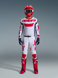 Motocross rider wearing the Alpinestars 2026 Racer Riway Gear Set, White jersey with red "astars" branding and blue side panels, white pants with red graphics, red racing helmet and boots, navy blue gloves, complete coordinated motocross racing outfit