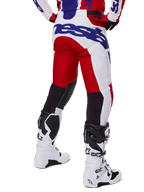 Alpinestars 2025 Racer Veil Pants, Motocross Pants, Bright Red and White with Blue branding, rear view showing black stretch ventilation panels on the back of the legs, paired with white motocross boots.