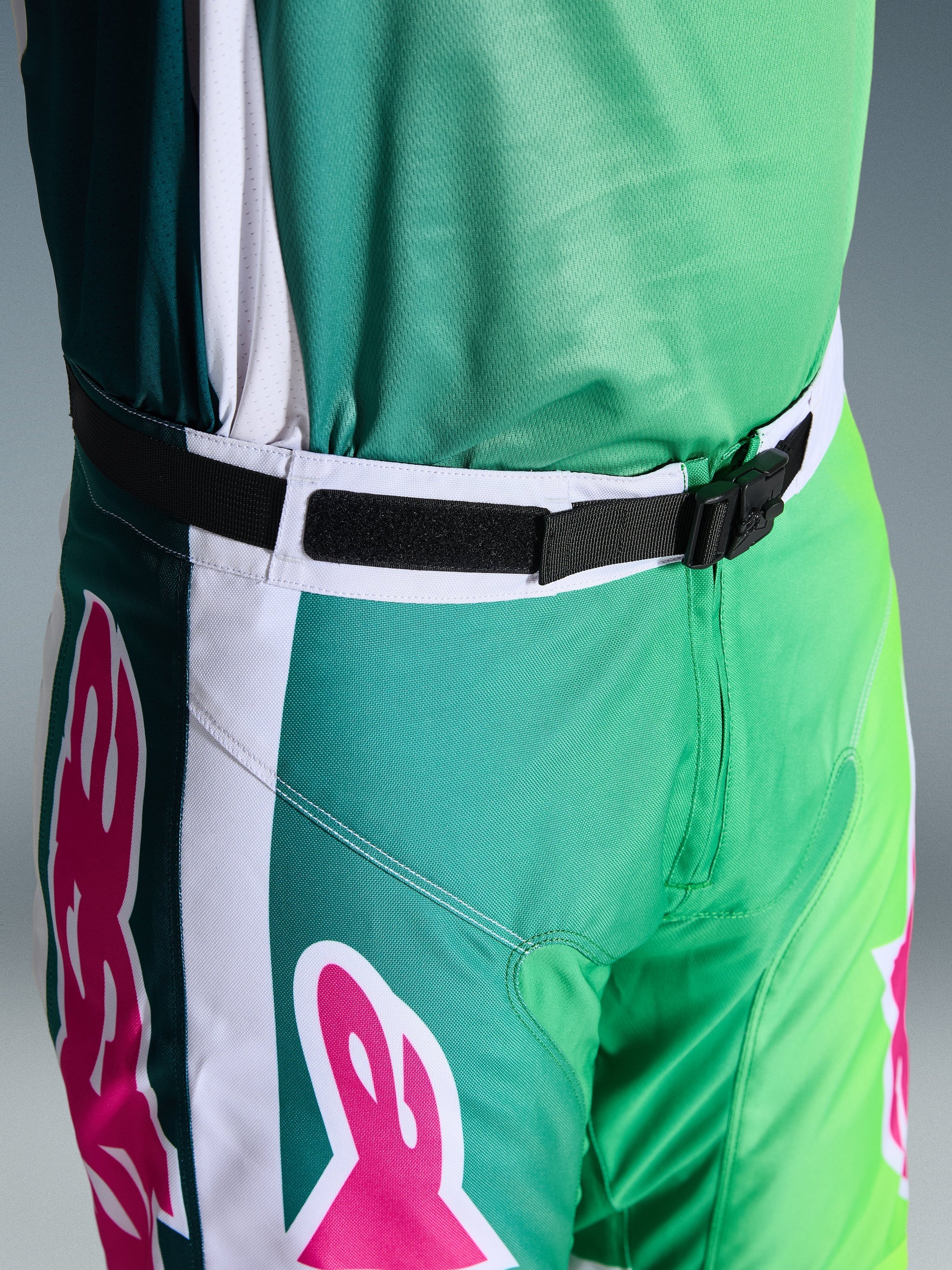 Alpinestars 2026 Racer Portl Pants, Motocross Pants, Green White and Black with Pink logo accents, close-up of the waist showing the SX2 magnetic buckle and adjustable closure, durable gear for off-road racing