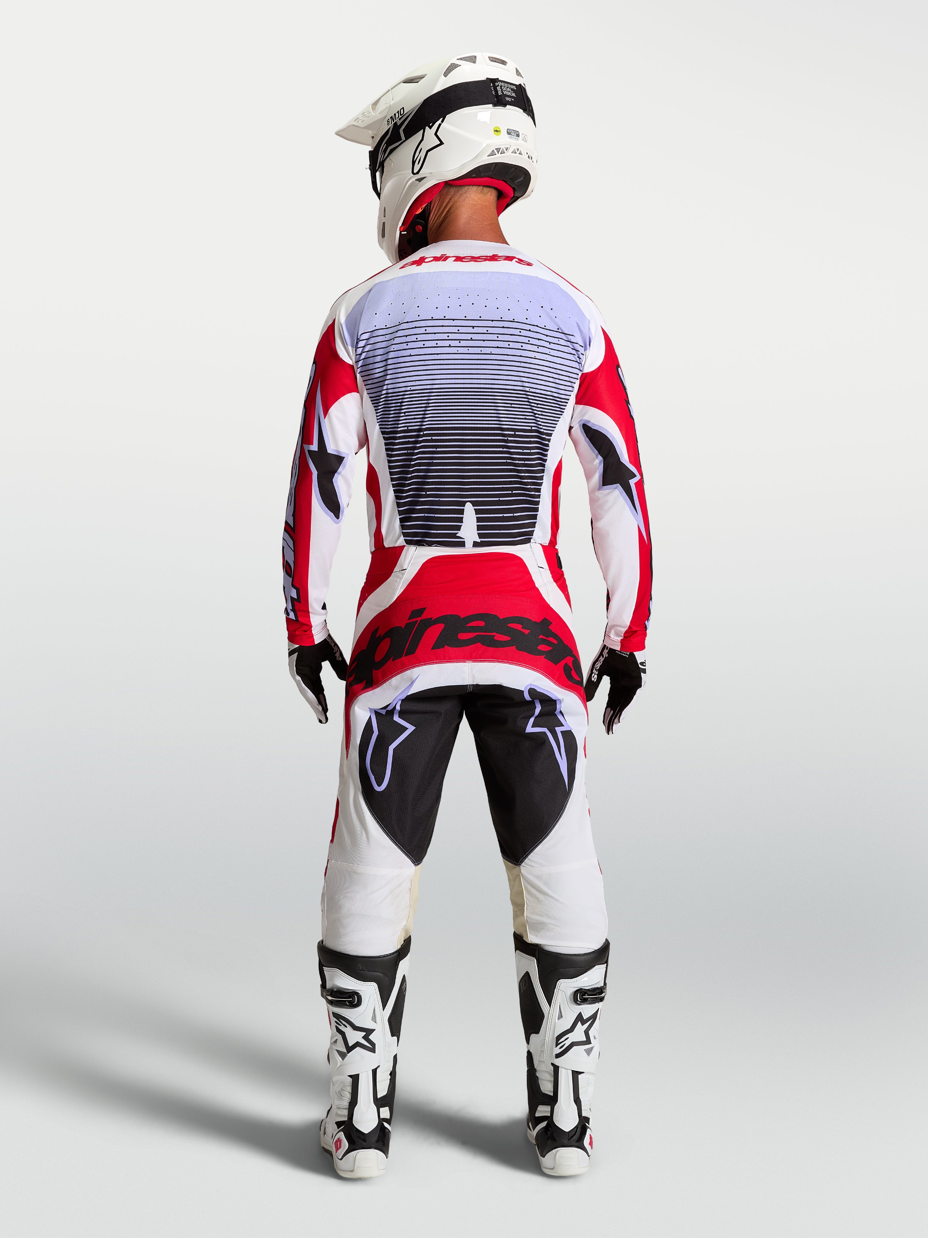 Alpinestars Techstar Maven motocross pants in Fire Red and White, rear view on a rider showing athletic race fit.