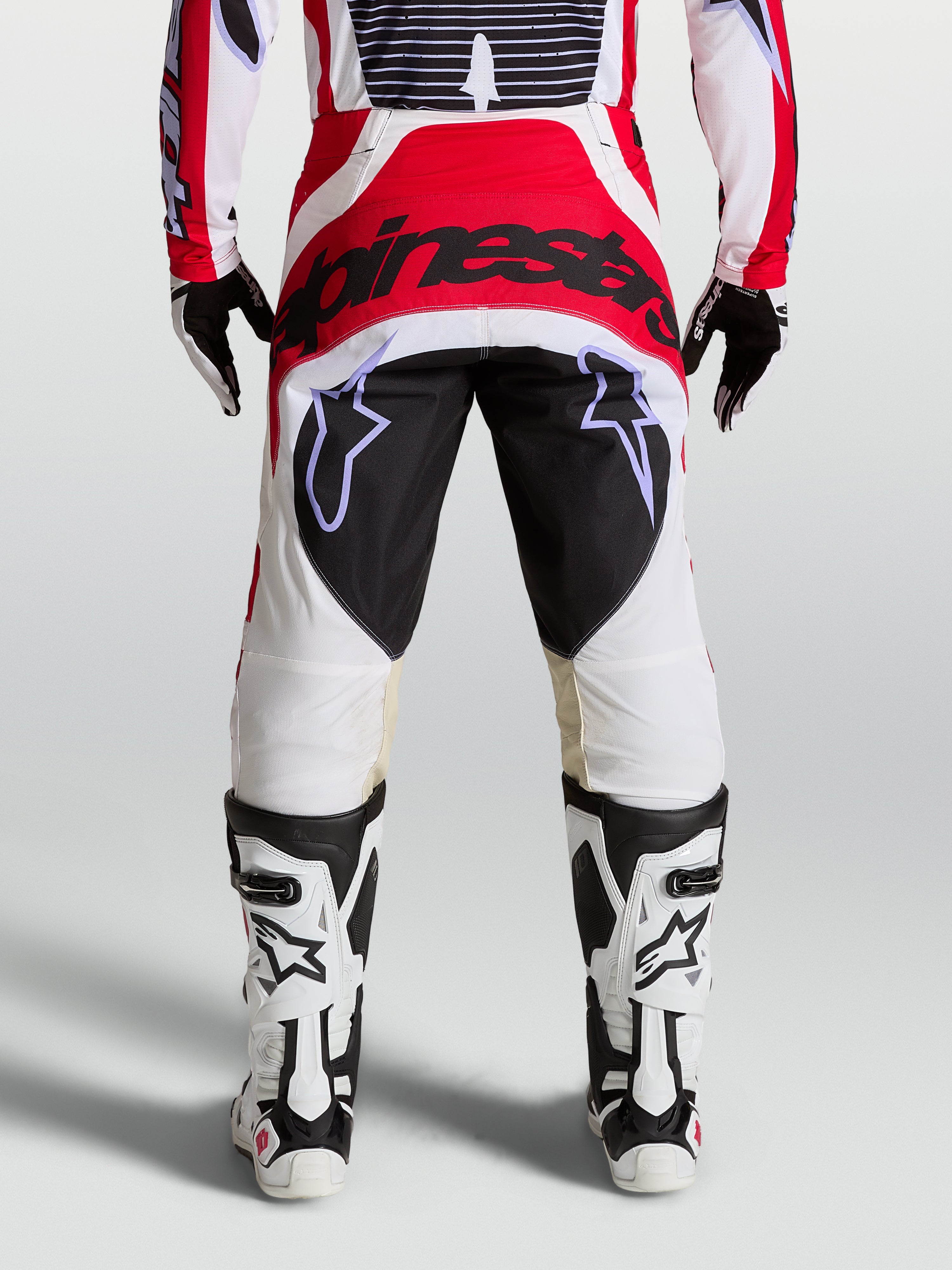 Alpinestars Techstar Maven motocross pants in red, white, and black, featuring a reinforced seat and athletic race fit.