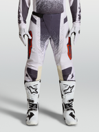 Alpinestars Techstar Swan Pants for motocross, Light Lilac and Dark Gray, featuring red accents and magnetic waist buckle, paired with white boots and gloves.